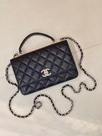 Dark navy quilted Chanel handbag with top handle and chain strap, angled front