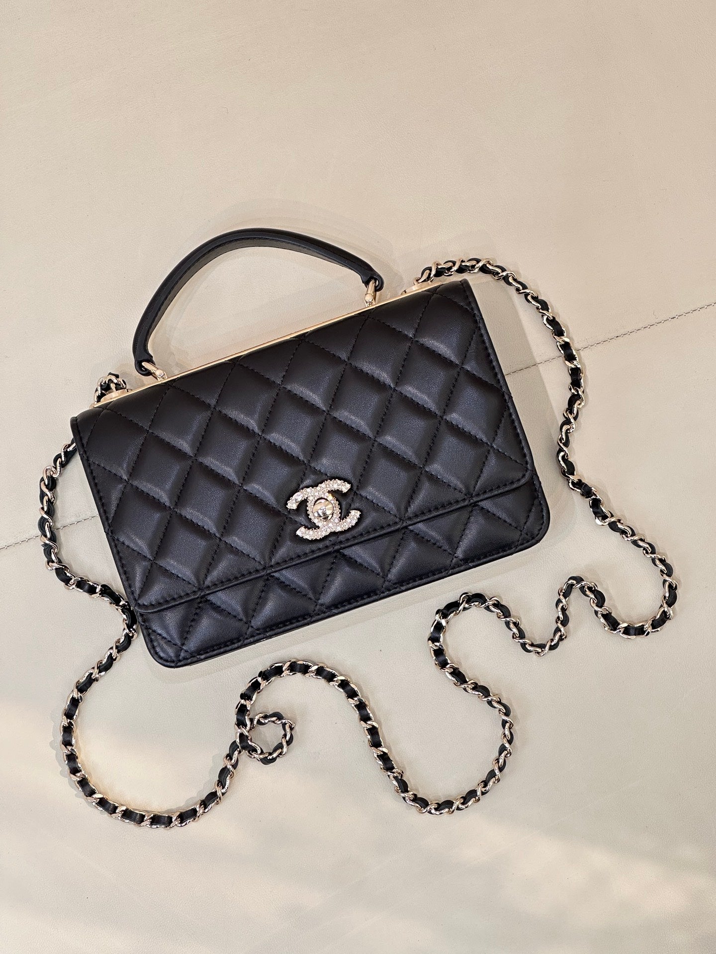 Dark navy quilted Chanel handbag with top handle and chain strap, angled front