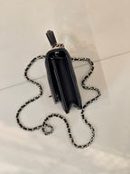 Dark navy Chanel handbag shown from back with chain strap and top handle