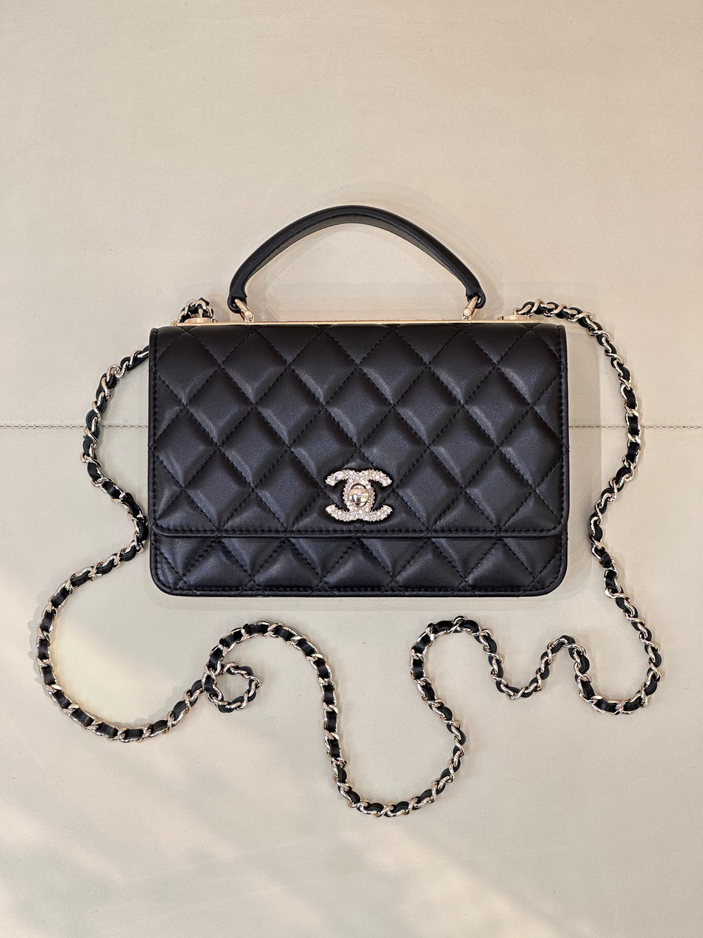Dark navy quilted Chanel handbag with top handle, chain strap, and front logo