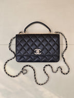 Dark navy quilted Chanel handbag with top handle, chain strap, and front logo