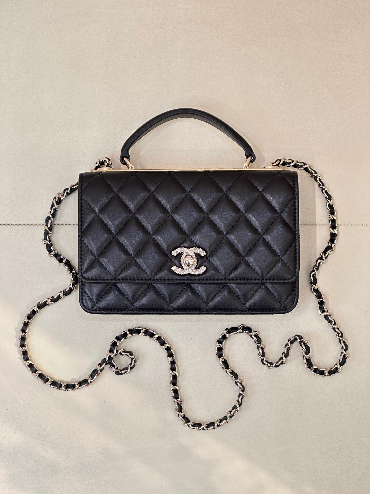 Dark navy quilted Chanel handbag with top handle, chain strap, and front logo