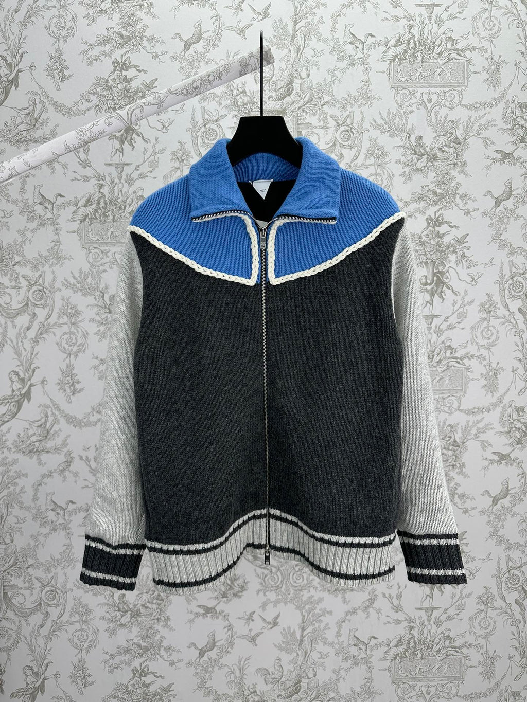 Zip-front knit vest with blue yoke and white trim, dark gray body, striped hem cuffs