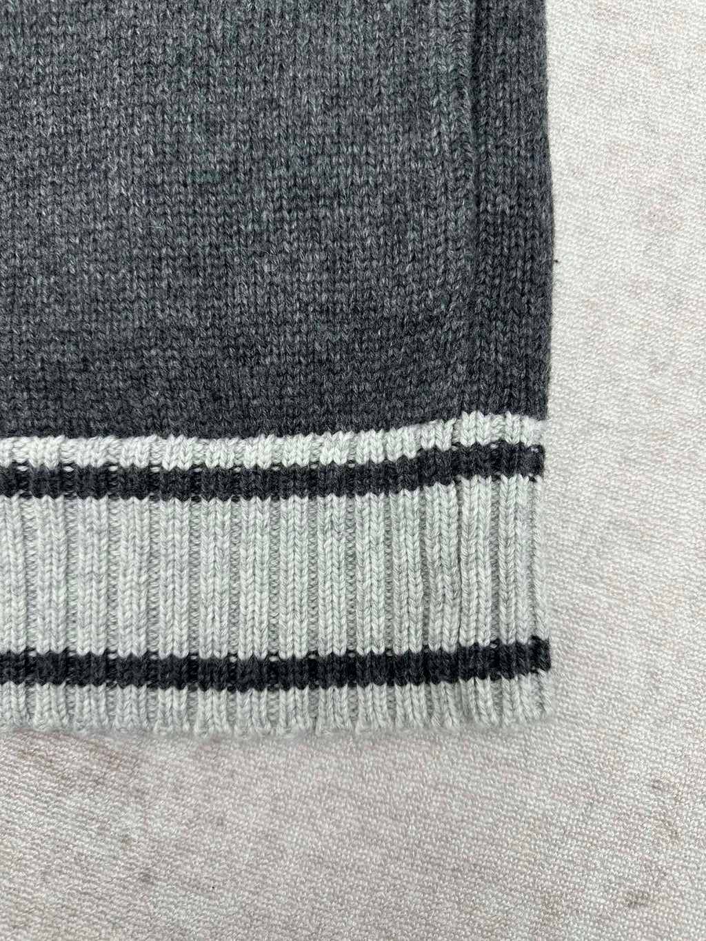 Ribbed hem band with white and black striped trim on dark knit sweater