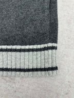 Ribbed hem band with white and black striped trim on dark knit sweater