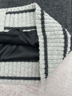 Cuffed sleeve edge with folded knit and white-black striped trim on dark gray vest