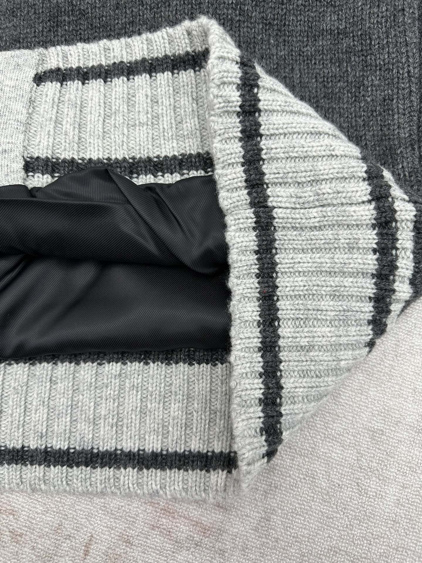 Cuffed sleeve edge with folded knit and white-black striped trim on dark gray vest
