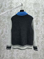 Back view of a zip-front knit vest with blue collar and white-striped cuffs on dark gray
