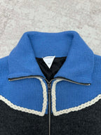 Knit vest neckline detail with blue collar, black lining, and zip with white trim