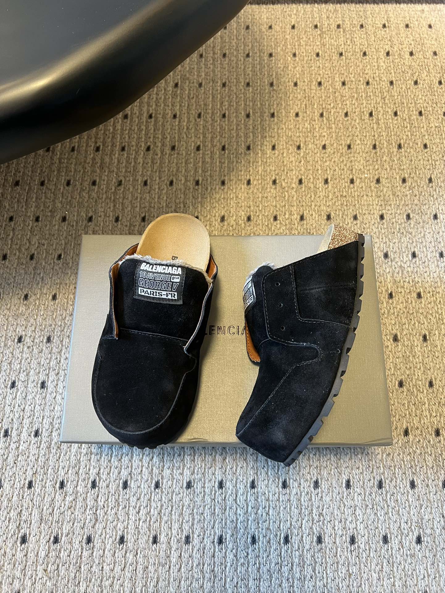Black suede slide sandals, showing front and side views with logo patch