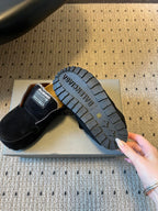 Black suede slide sandals showing textured rubber outsole tread