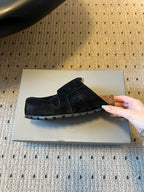 Black suede slip-on sandals with textured rubber sole and logo patch