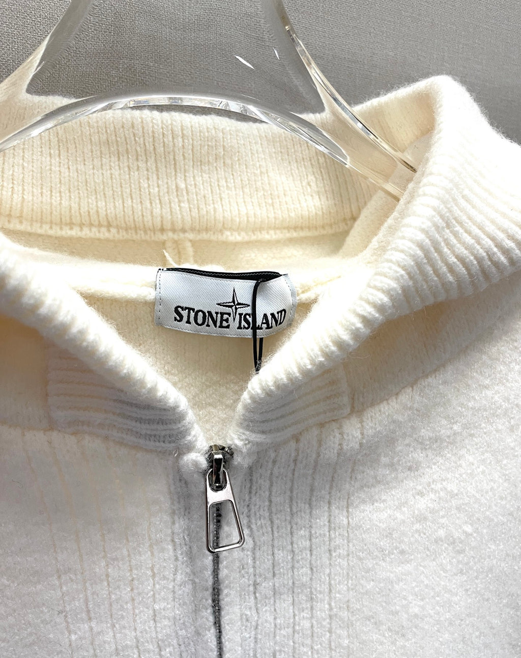 White zip-up hoodie close-up at hood opening with Stone Island logo tab