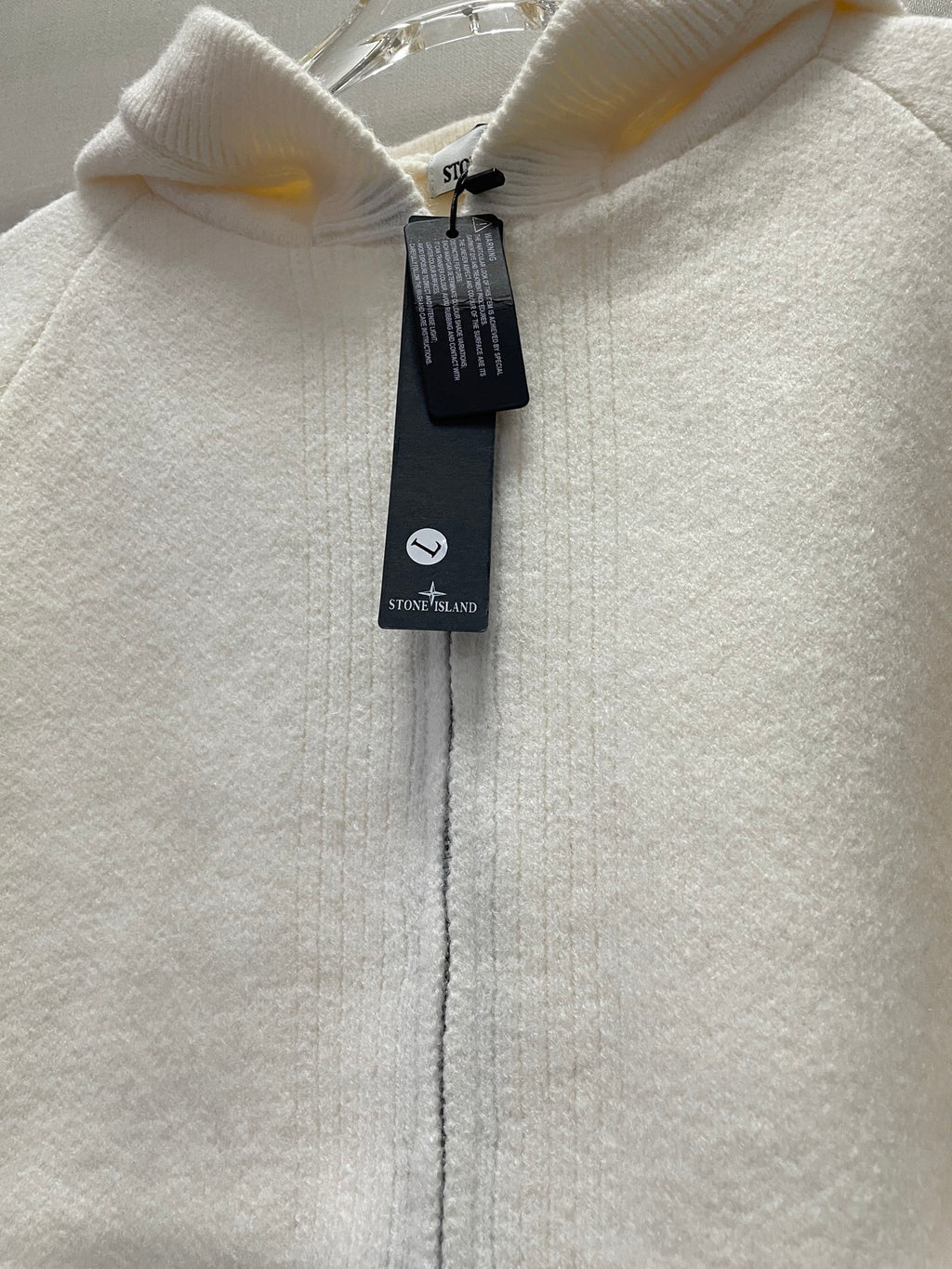 White hoodie zipper and hood close-up with hanging Stone Island tag