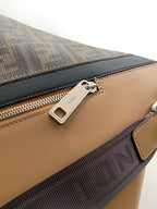 Close-up of tan leather panel and zip track on dark monogram bag