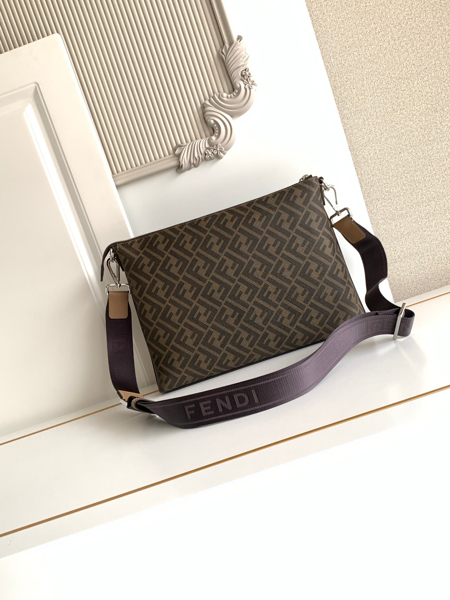 Brown and dark monogram crossbody bag with adjustable strap and metal hardware