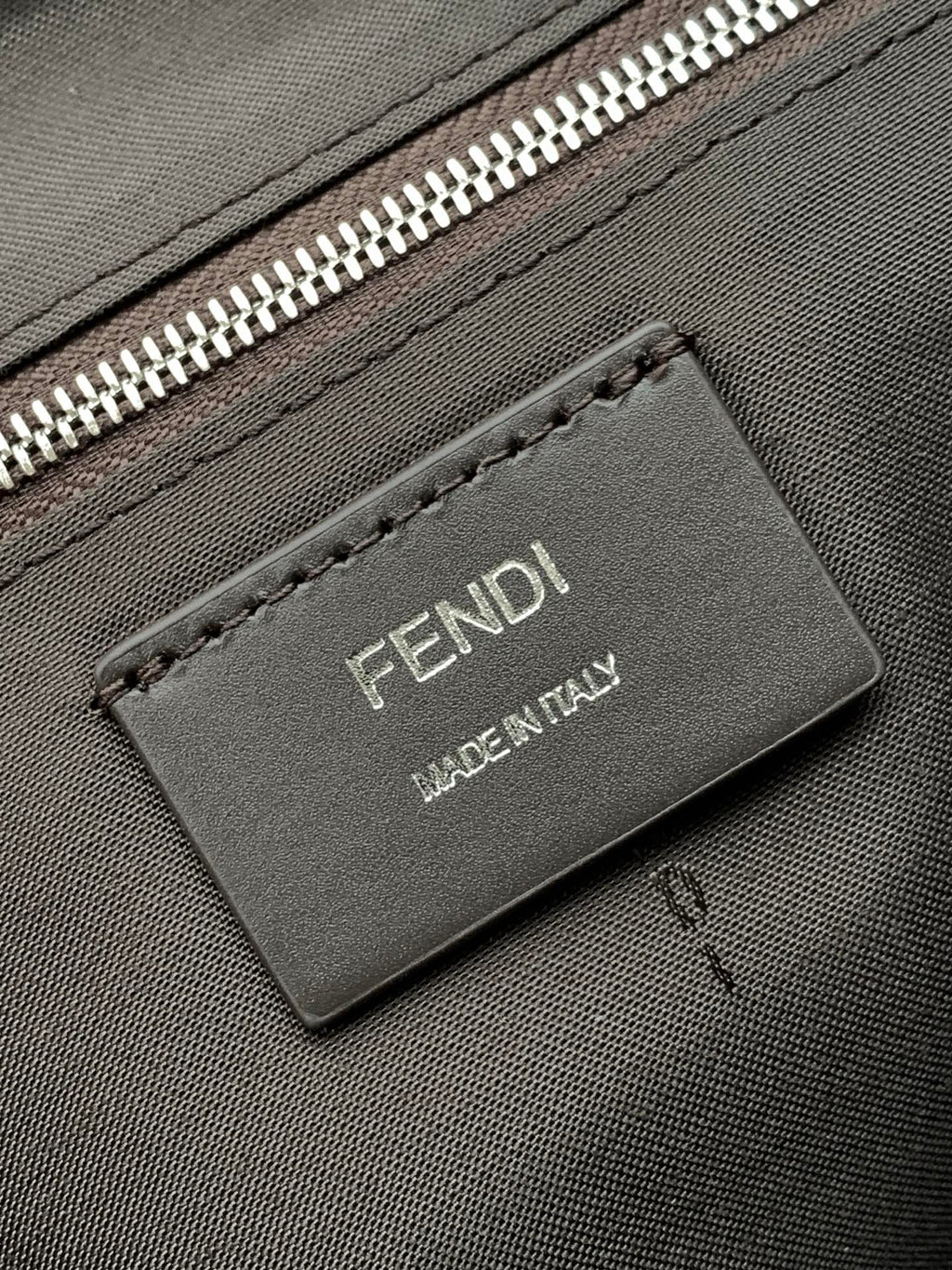 Leather logo patch reading FENDI MADE IN ITALY on textured bag
