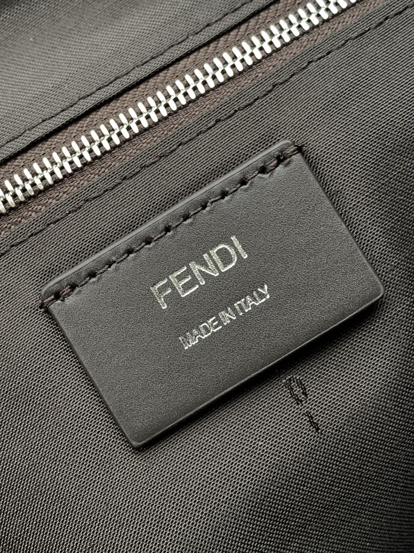 Leather logo patch reading FENDI MADE IN ITALY on textured bag