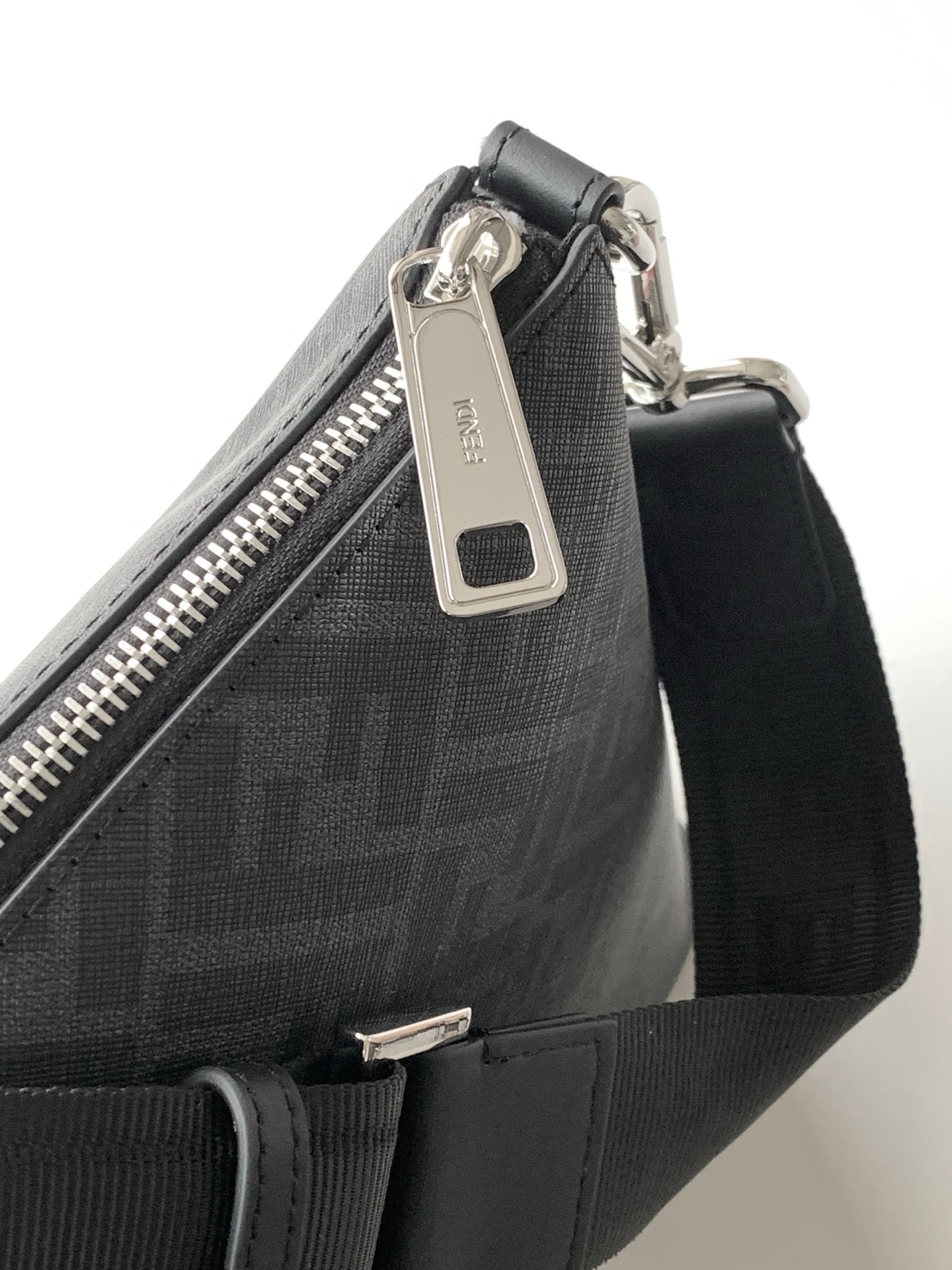 Fendi bag close-up of top zipper pull and logo hardware on dark fabric