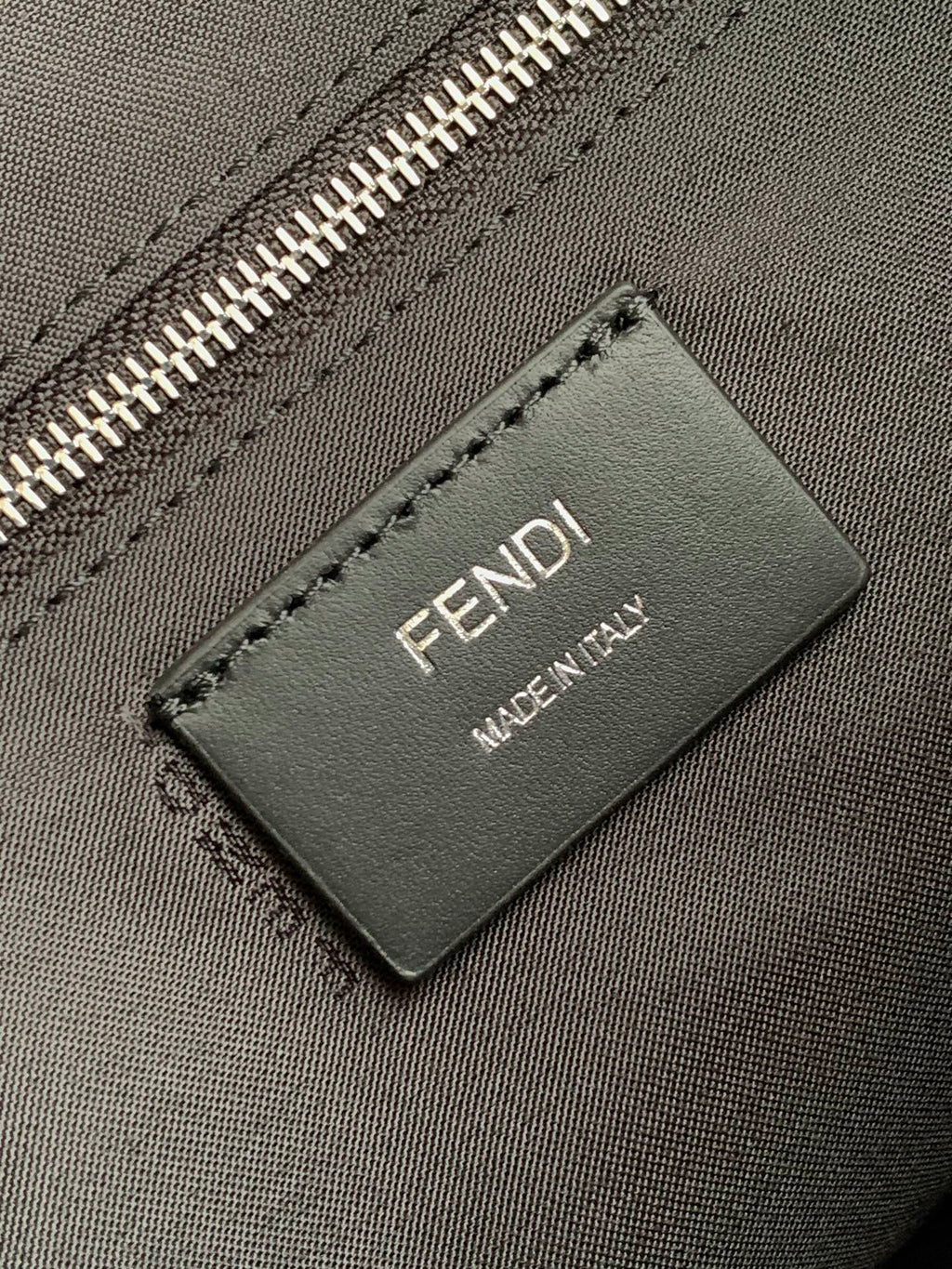 Fendi leather brand tag reading FENDI MADE IN ITALY on dark bag