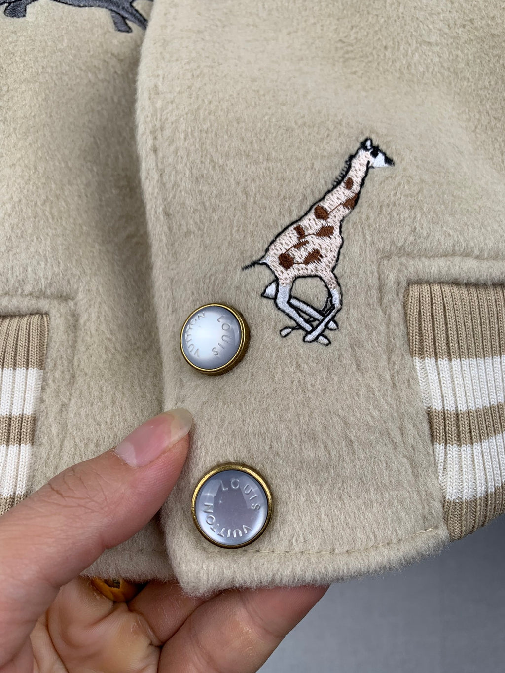 Beige Louis Vuitton pocket area with embroidered giraffe and round metal-look buttons