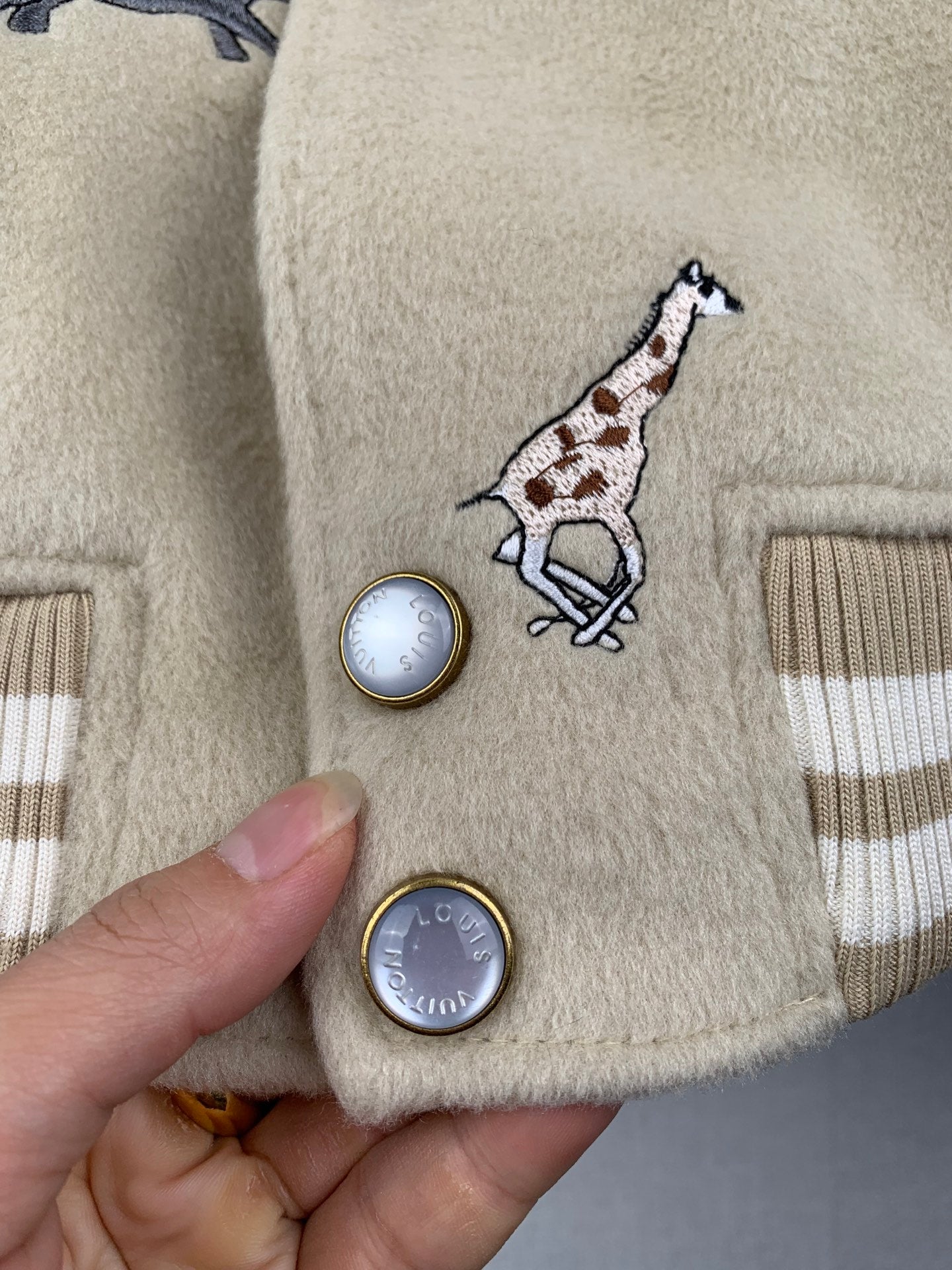 Beige Louis Vuitton pocket area with embroidered giraffe and round metal-look buttons