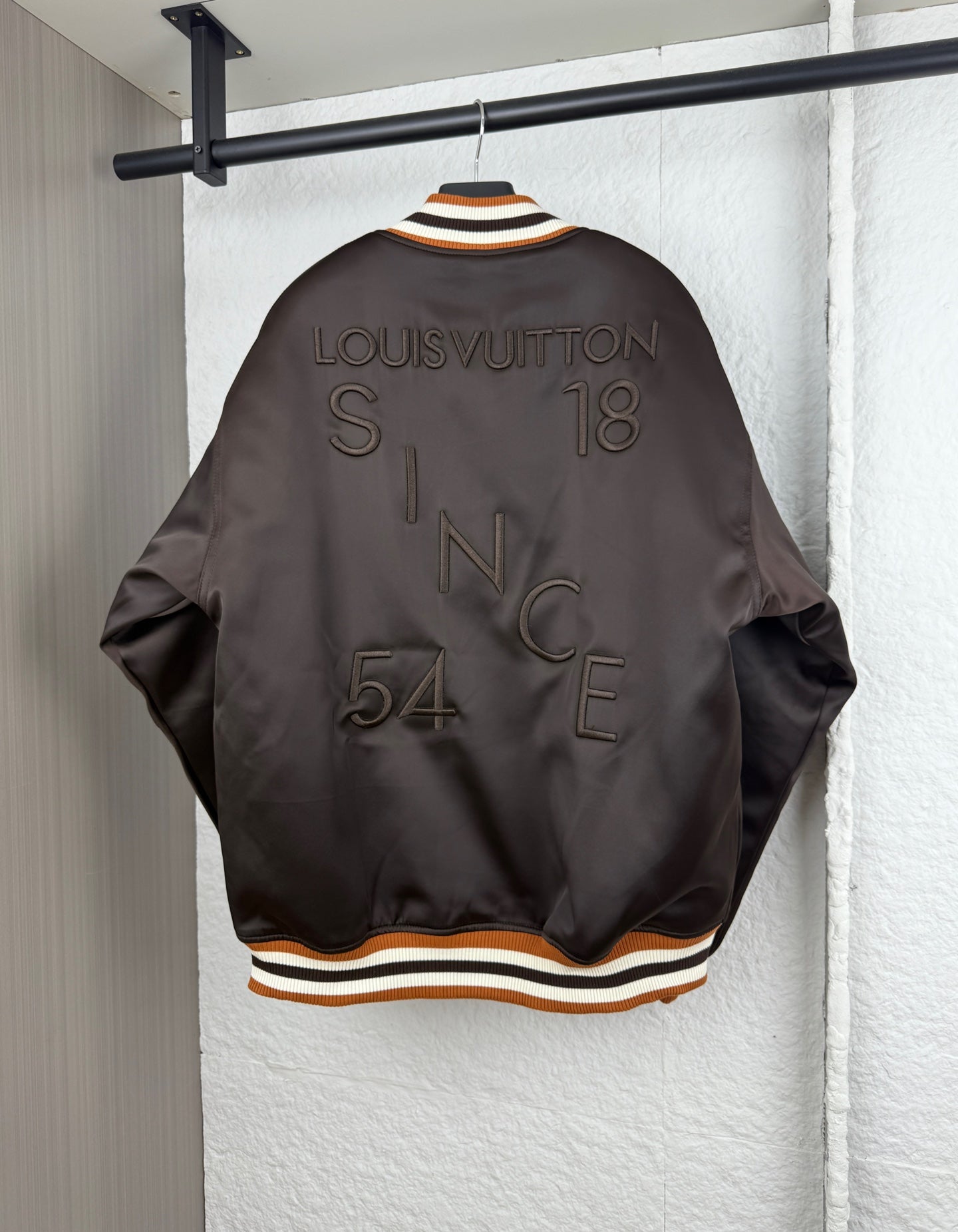 Back view of bomber jacket with striped ribbed collar and rhinestone-style lettering