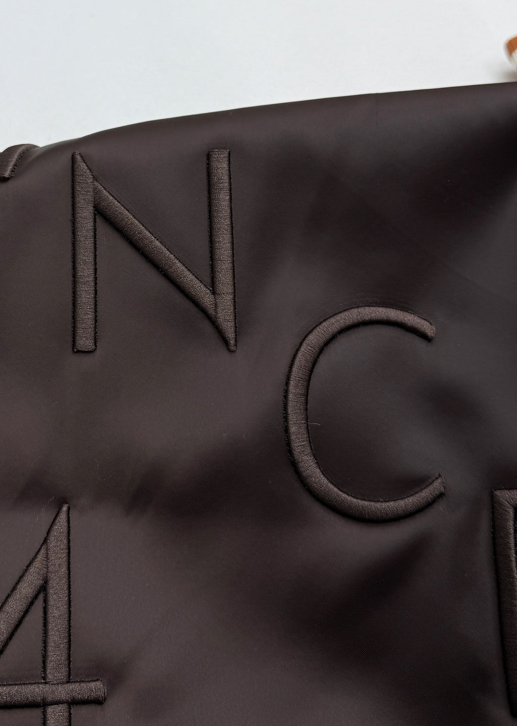 Close-up of bomber jacket “IN” lettering patch on dark fabric