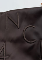 Close-up of bomber jacket “IN” lettering patch on dark fabric