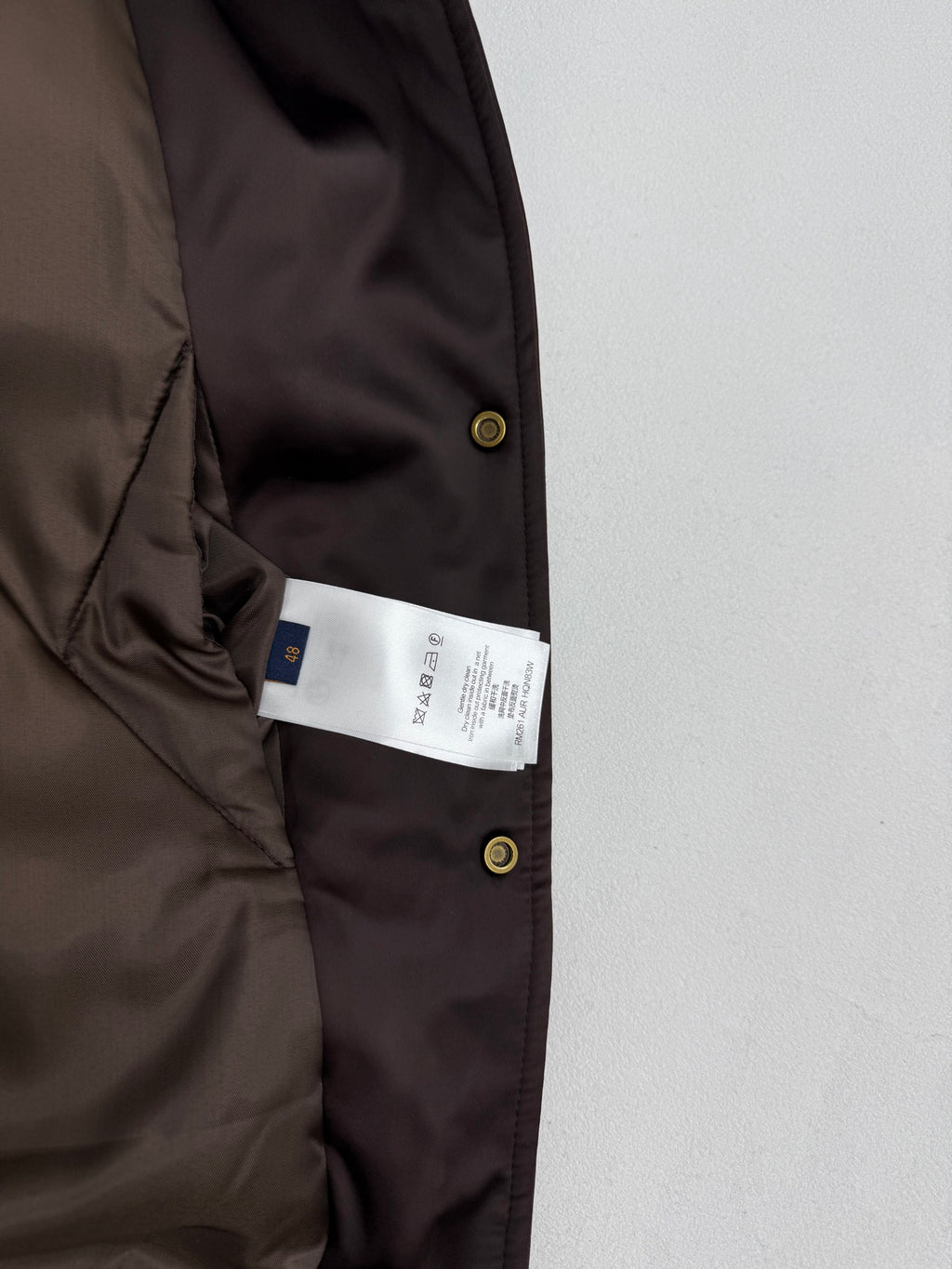 Bomber jacket with interior size tag visible near button placket