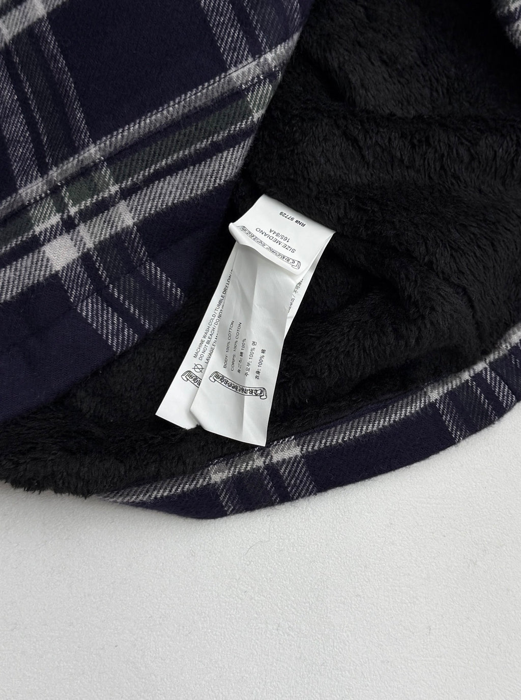 Plaid shirt-jacket inner lining with white brand label tag on navy fabric