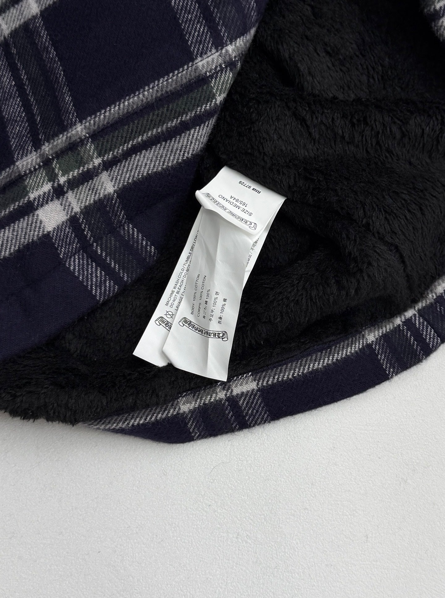 Plaid shirt-jacket inner lining with white brand label tag on navy fabric