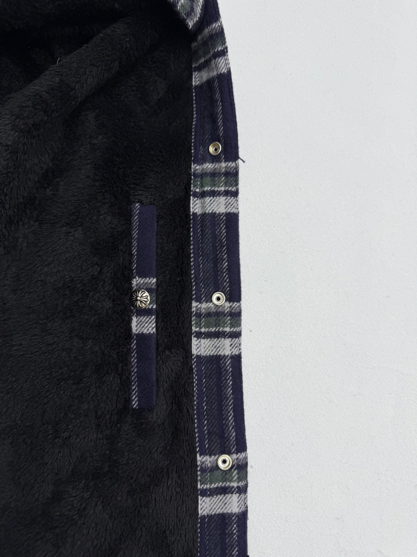 Plaid shirt-jacket side seam and pocket detail with metal snaps, navy and white checks