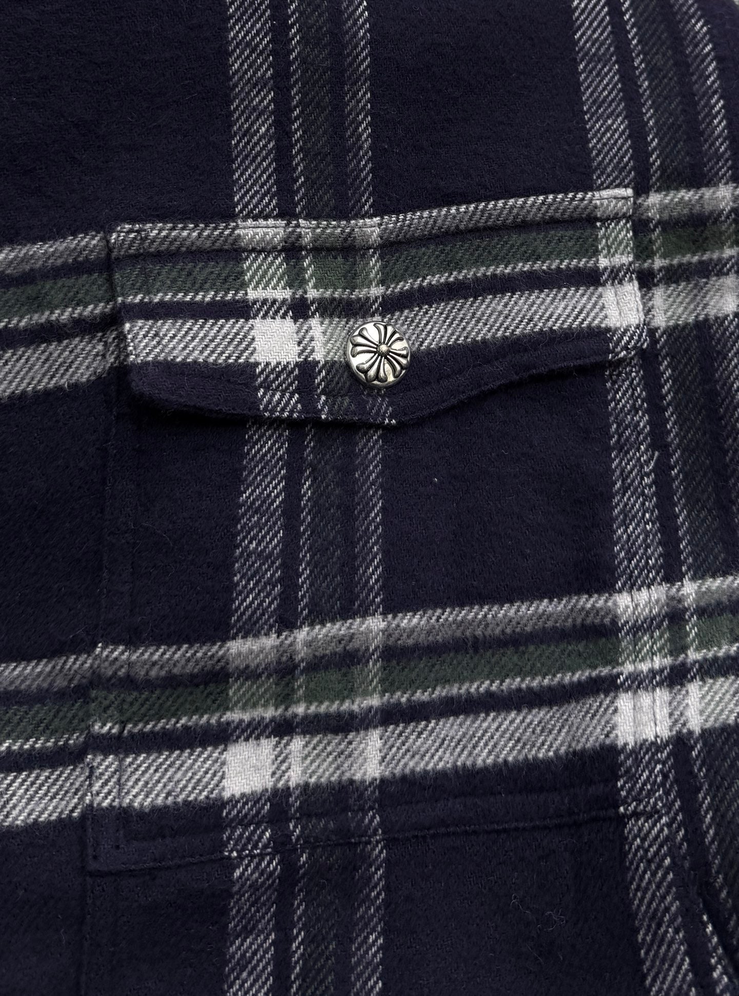 Plaid shirt-jacket chest pocket flap with metal button, navy and white grid pattern