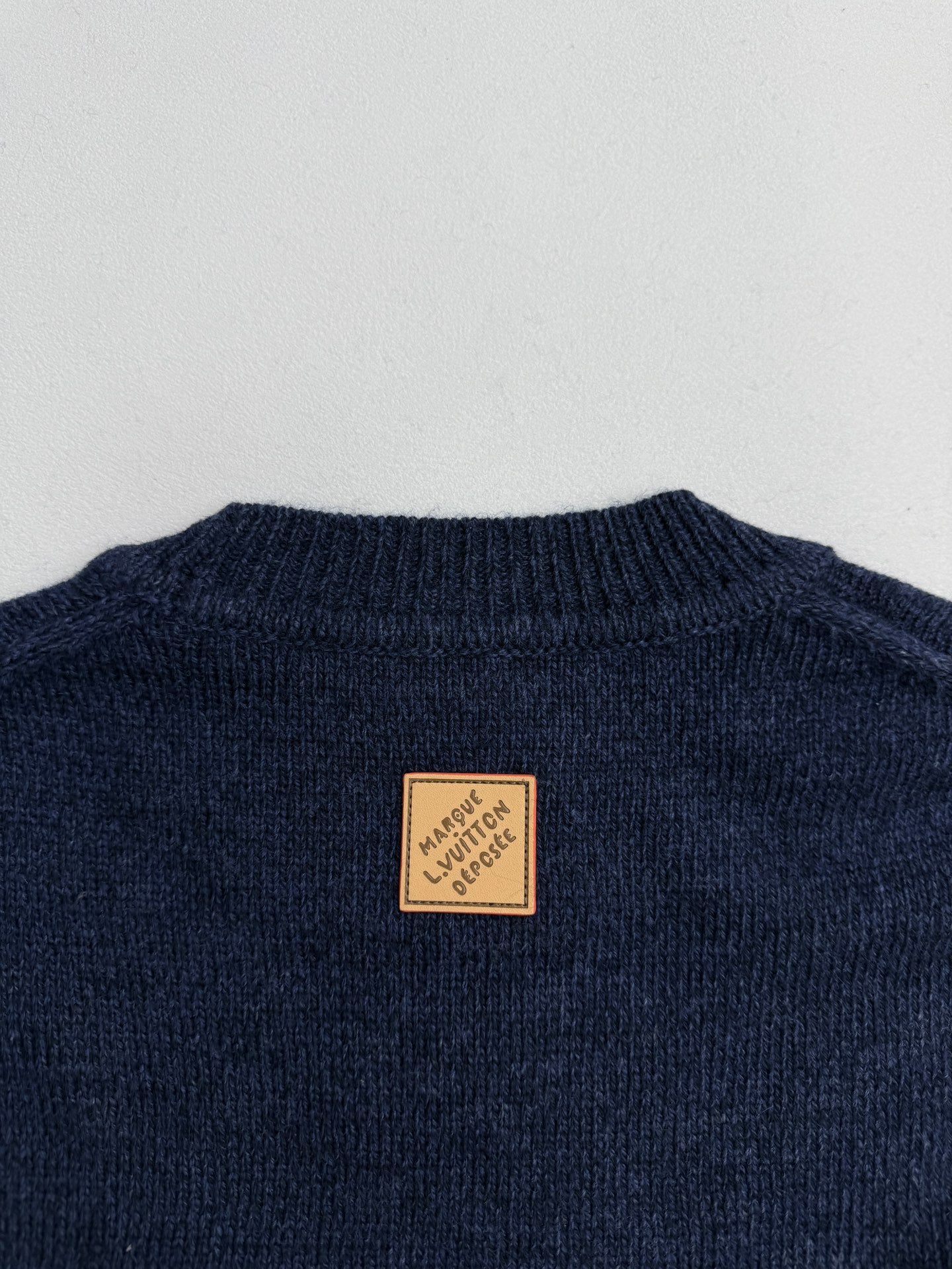 Navy knit sweater back neckline with brown brand patch label