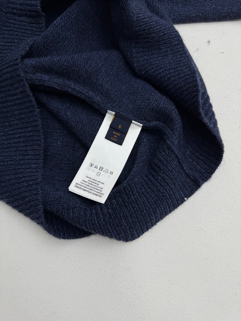 Navy knit sweater collar with white fabric care label