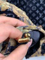 Louis Vuitton long jacket fastener detail, dark strap with gold button and emblem