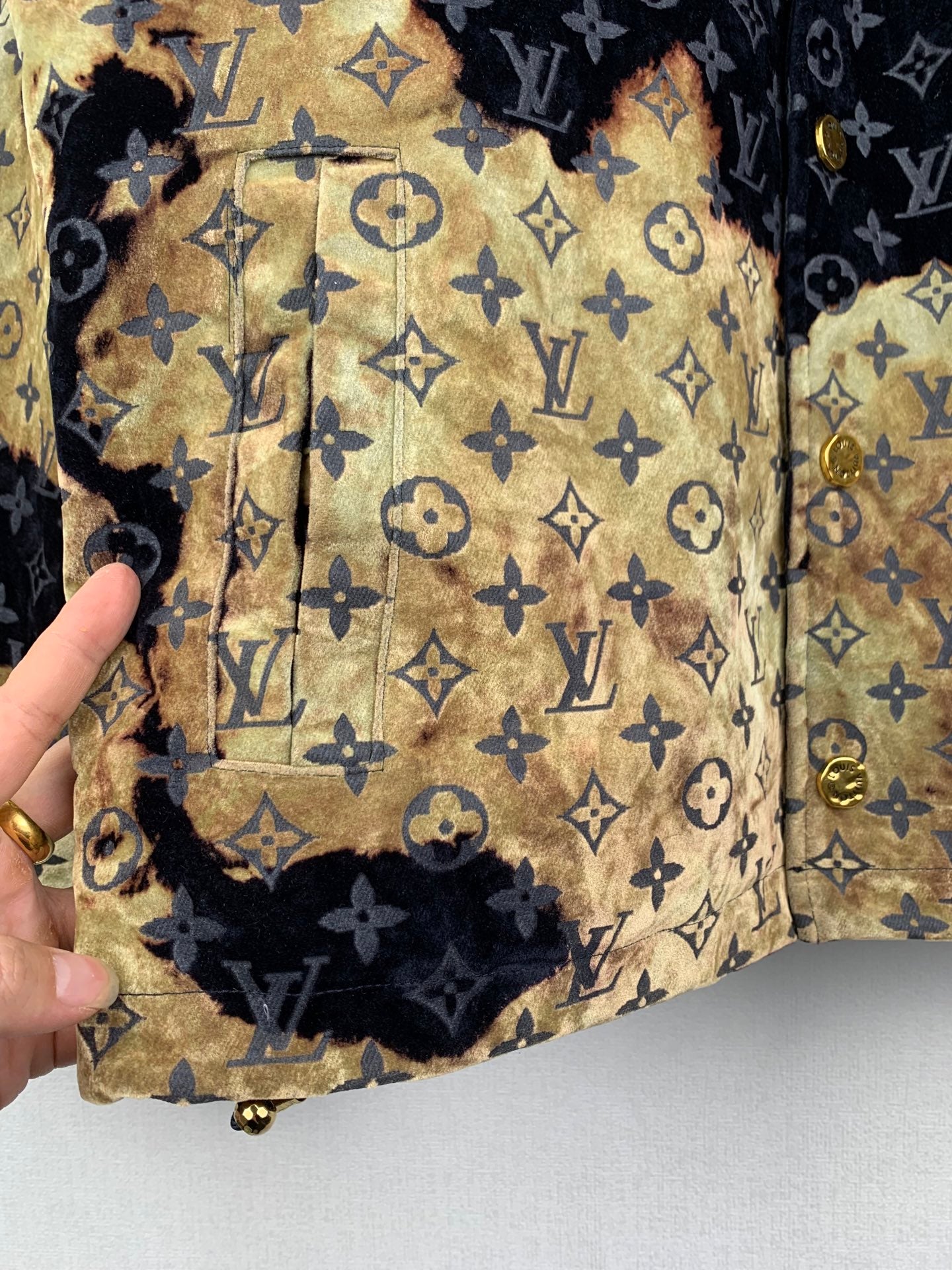Louis Vuitton long jacket panel close-up, tan-gold fabric with navy monogram pattern