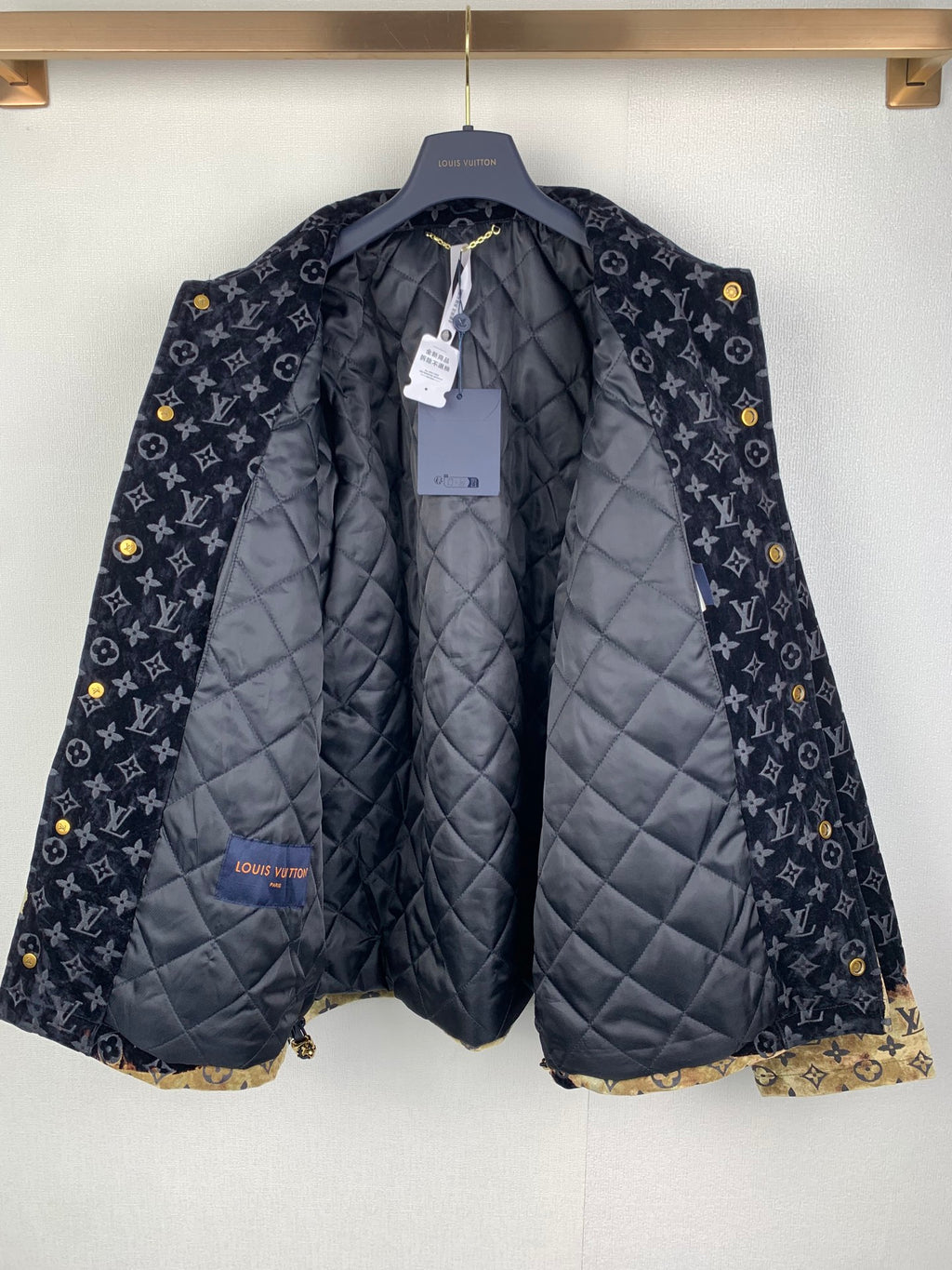 Quilted long jacket on hanger with dark monogram outer and padded lining