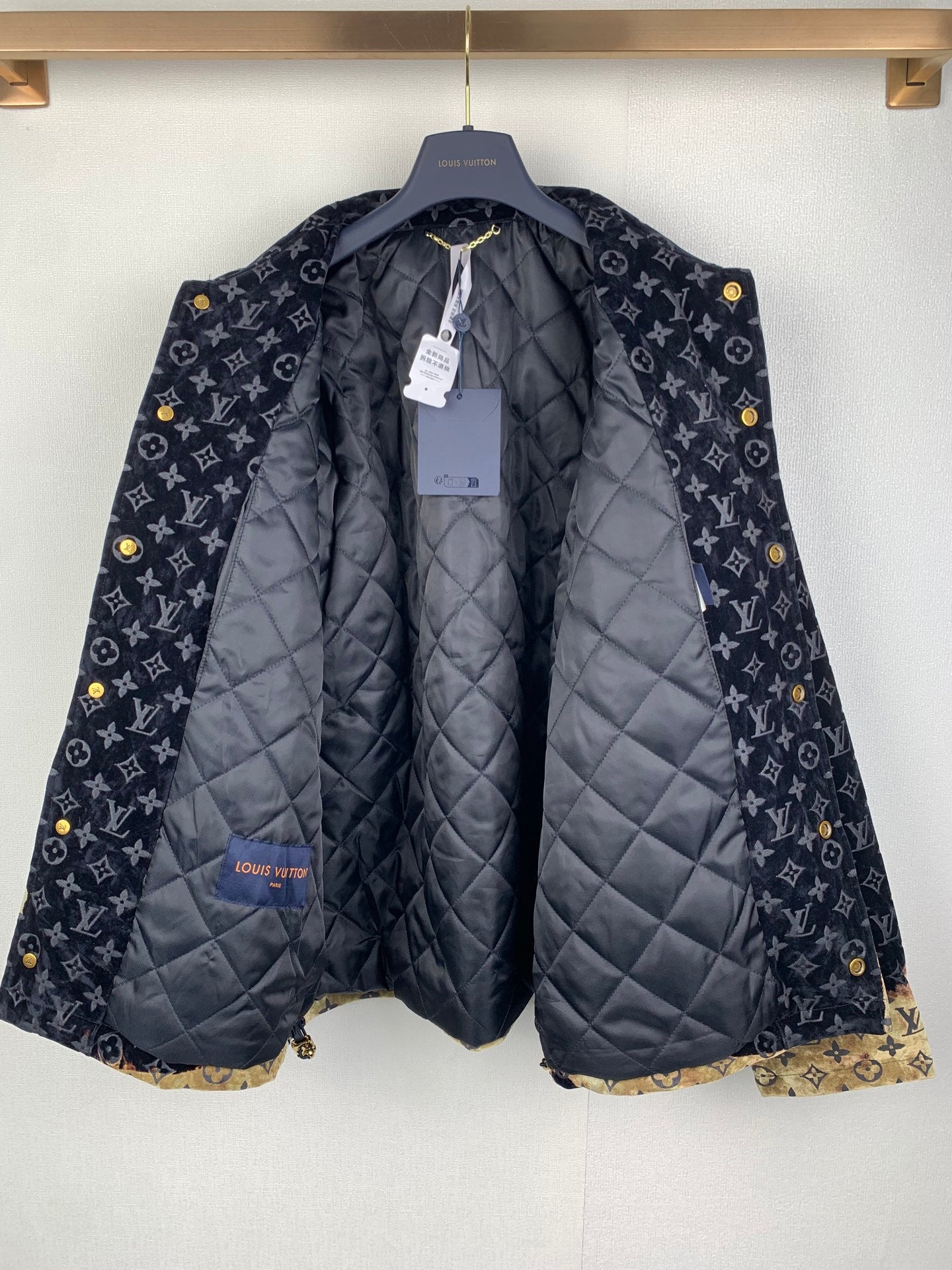 Quilted long jacket on hanger with dark monogram outer and padded lining