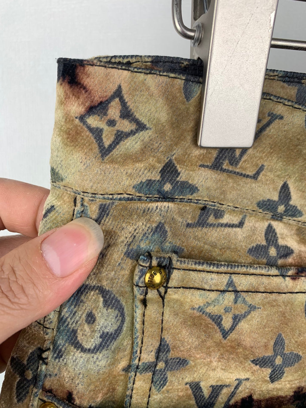Louis Vuitton monogram long pants fabric close-up with tan patch and dark motifs