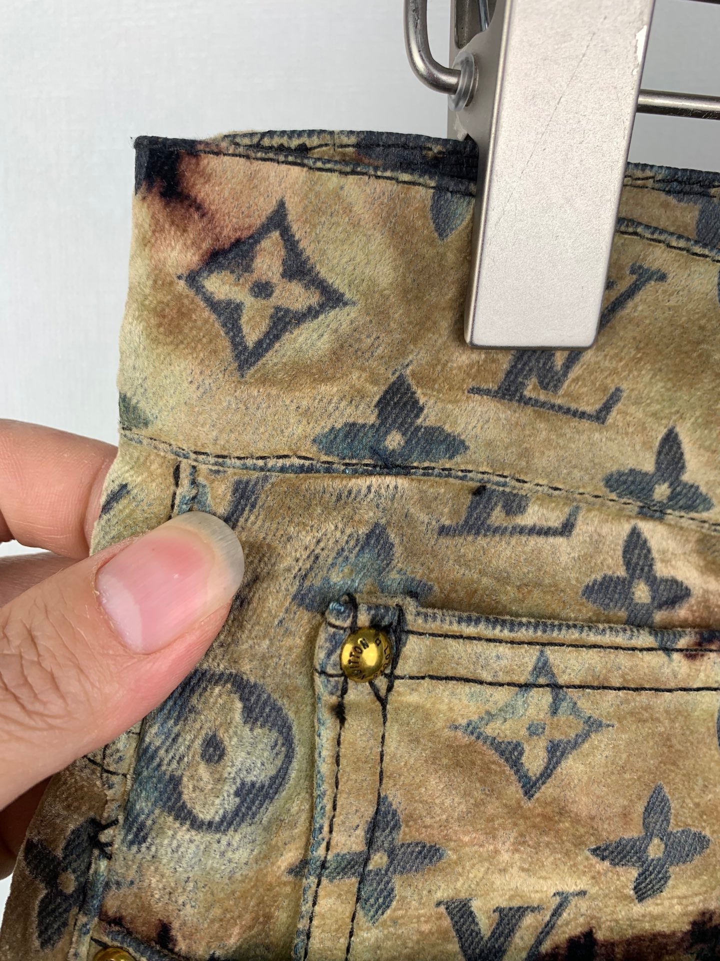 Louis Vuitton monogram long pants fabric close-up with tan patch and dark motifs