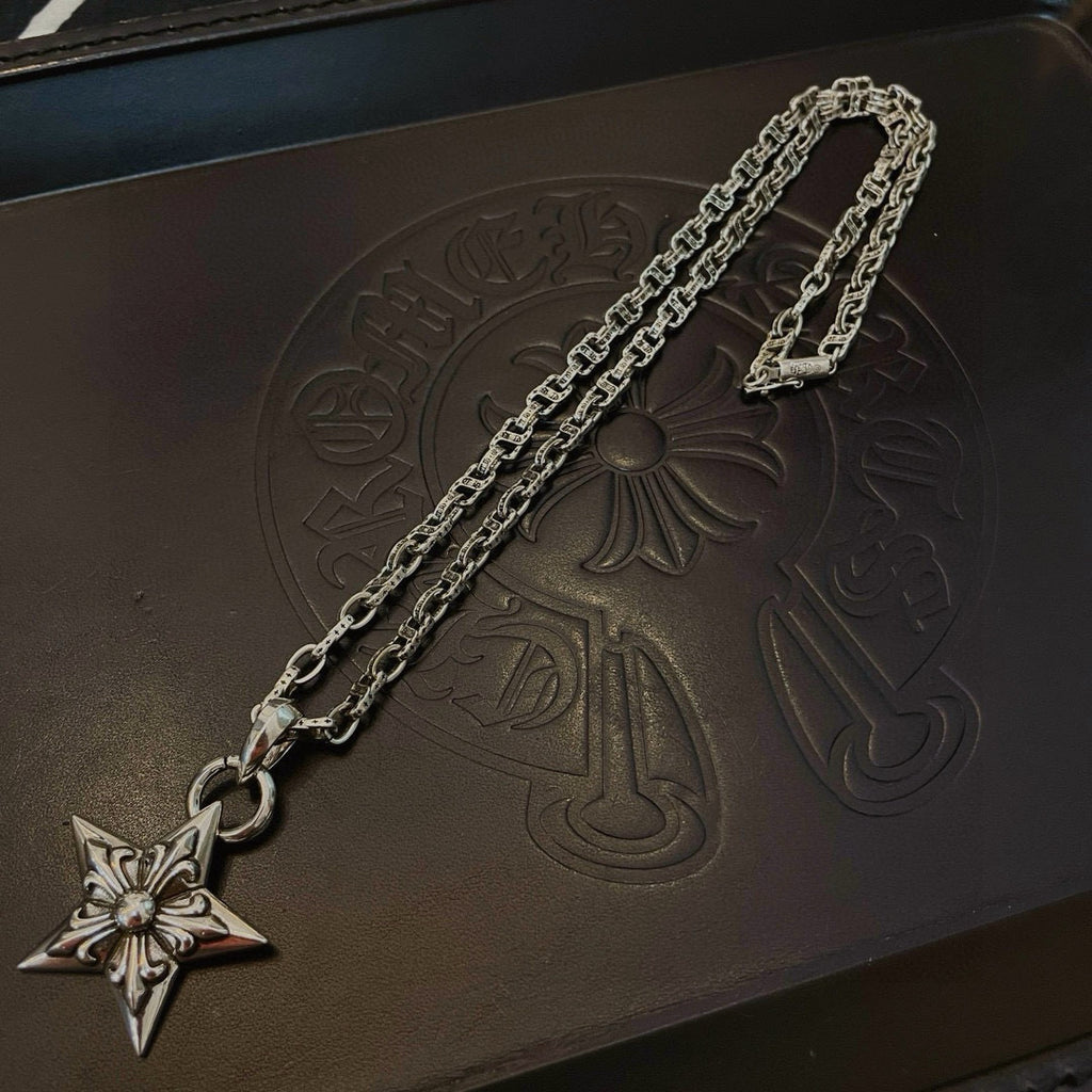 Silver chain necklace with star pendant on dark box lid, close-up