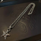 Silver chain necklace with star pendant on dark box lid, close-up