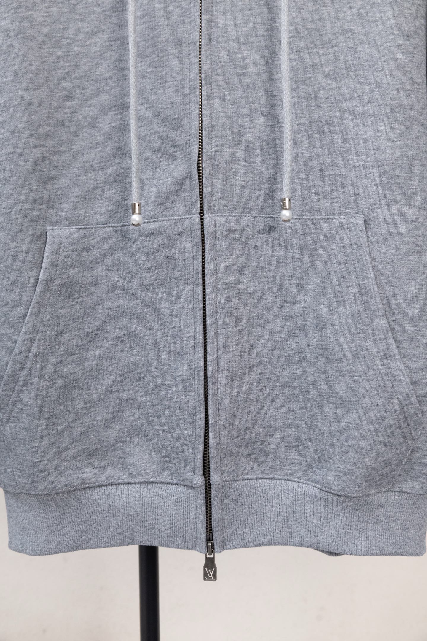 Light gray zip-up hoodie with kangaroo pocket and two drawstring cords.
