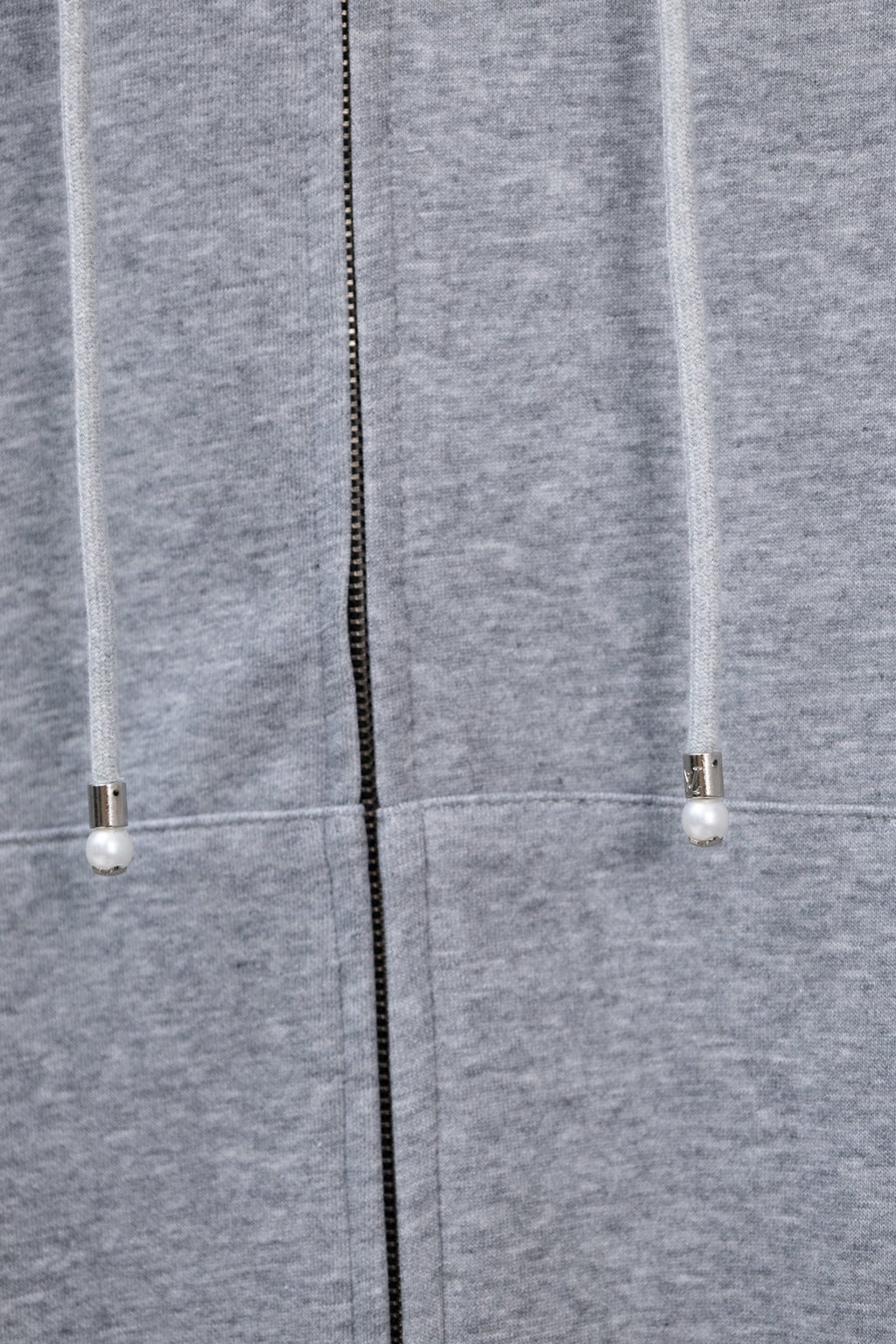 Light gray hoodie showing center zipper and drawstring ends with small beads.