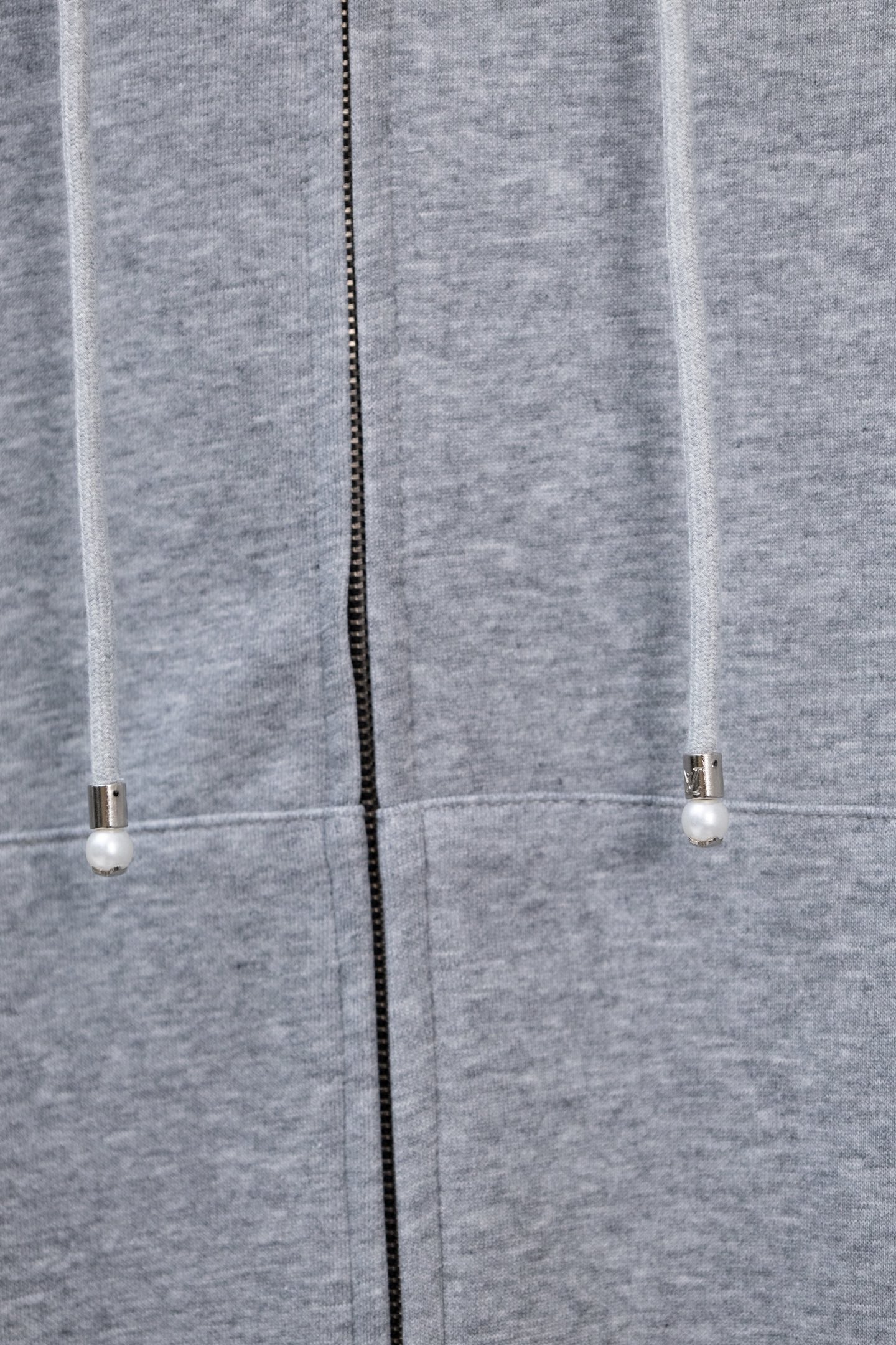 Light gray hoodie showing center zipper and drawstring ends with small beads.