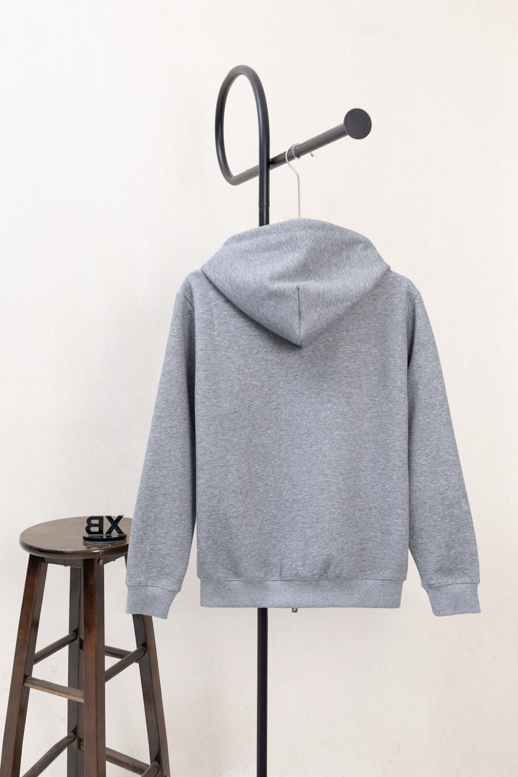Light gray hoodie from back view with hood and drawstring cords, long sleeves.