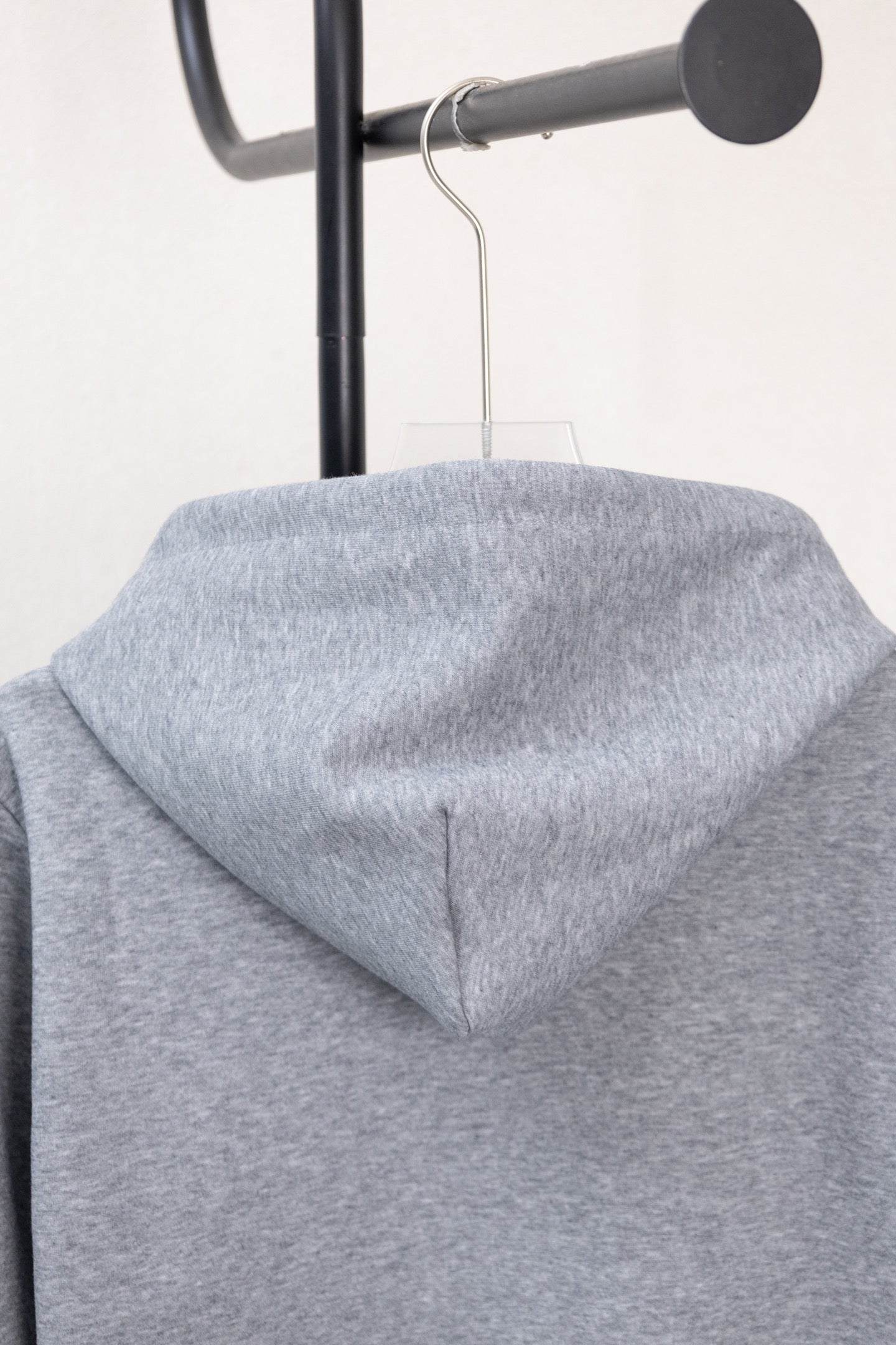 Light gray hoodie with draped hood and centered seam detail, no front zipper shown.