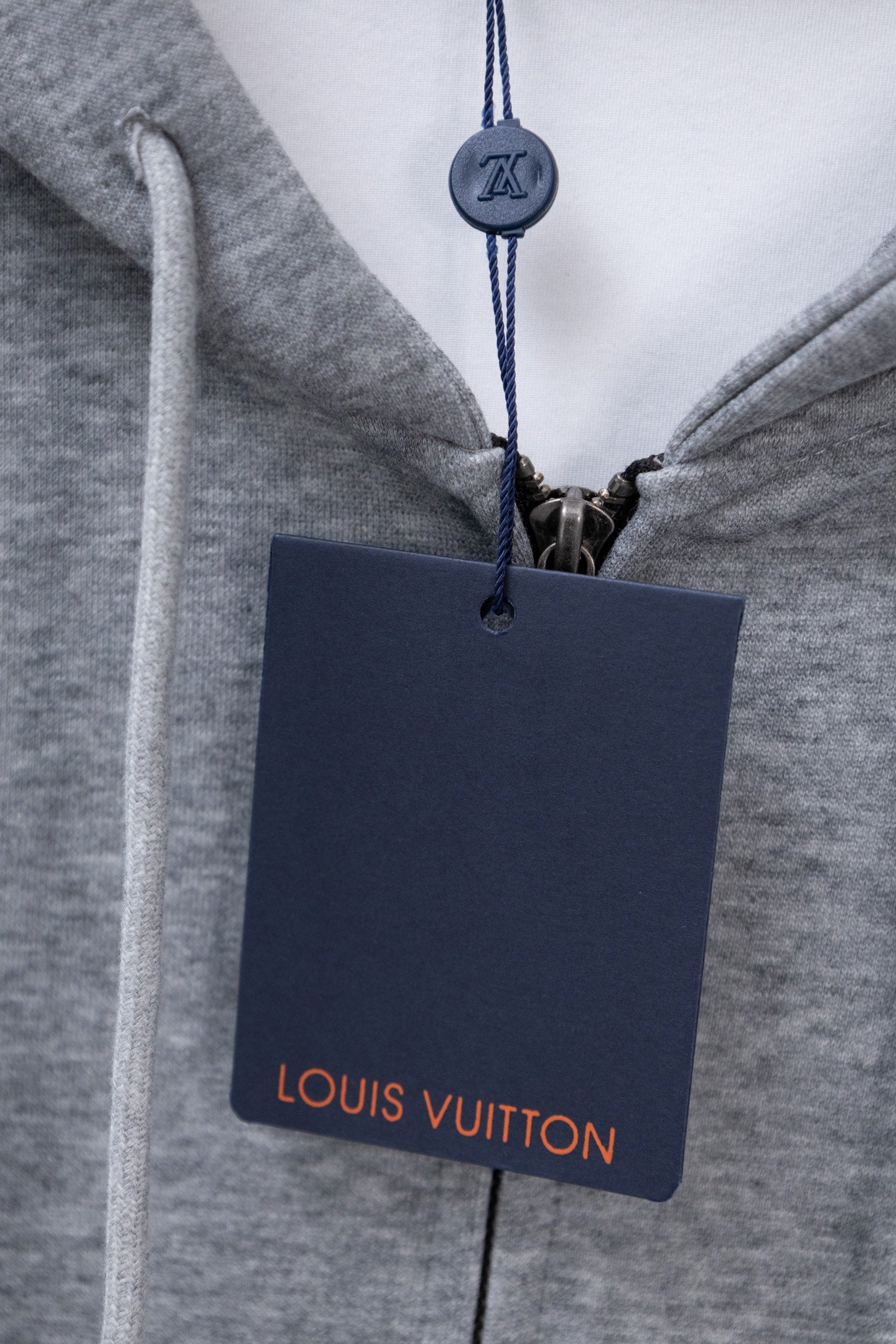 Light gray hoodie with Louis Vuitton hang tag on drawstring cord.